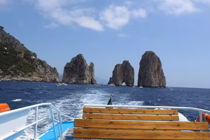 Boat approaches iconic Faraglioni rock formations on Capri mini cruise with time for swimming and exploration.