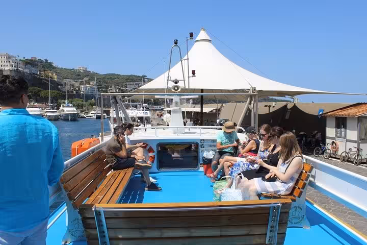 Passengers relax on deck as Capri mini cruise departs marina for island adventure with swim stop.