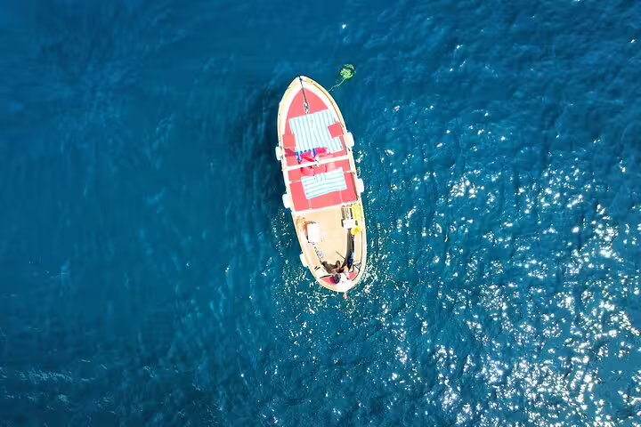 Aerial view of private boat on sparkling blue sea, full-day sea day tour with swim stops and relaxation