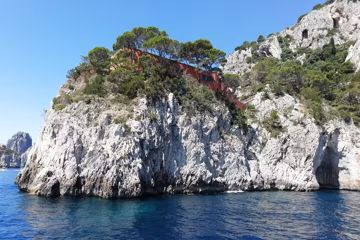 Picturesque rocky cliff with lush greenery and vibrant colors, perfect for exploring during a Capri tour.