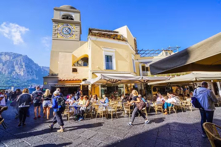 Bustling Capri square with cafes and iconic clock tower, a highlight on the Naples hydrofoil tour.