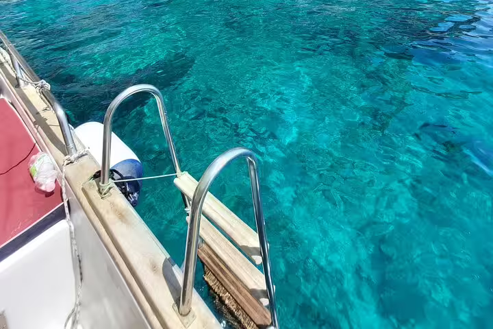 Swim ladder off private boat in crystal-clear turquoise sea on full-day Sea Day Charm and Freedom tour