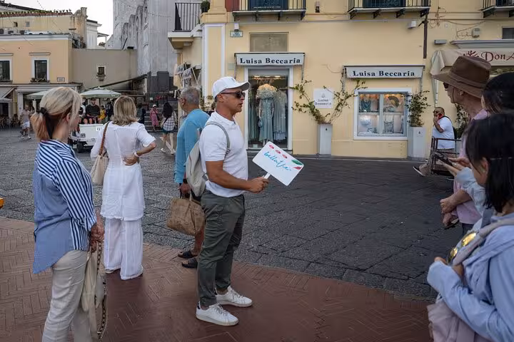 A tour guide holding a sign, leading a group of tourists through the charming streets of Capri.