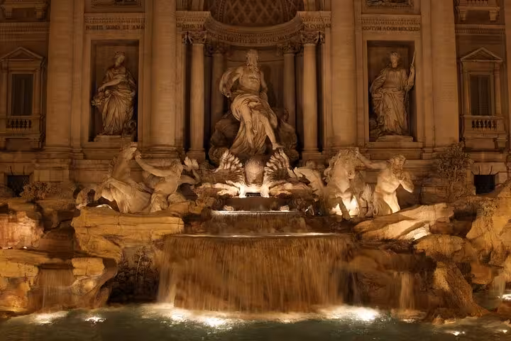 Illuminated Trevi Fountain at night in Rome, featuring majestic sculptures and cascading water for city tours.