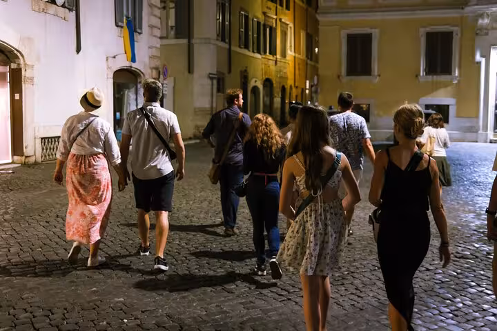 Group of tourists exploring Rome's charming cobblestone streets during the Bone Crypts and Dark Centre Tour.