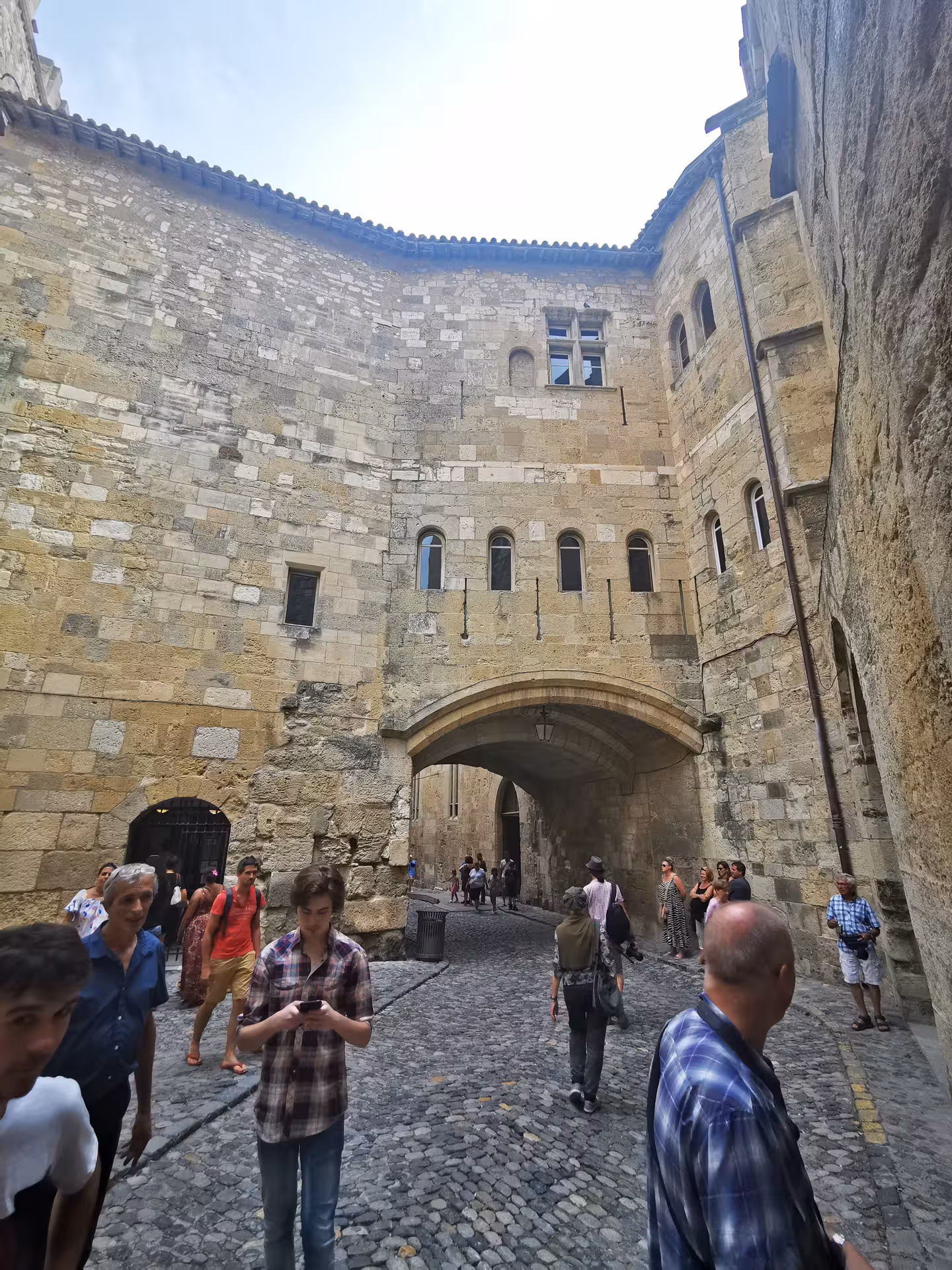 Tourists walk beneath Carcassonne medieval stone archway on private shore excursion from Sète to Narbonne
