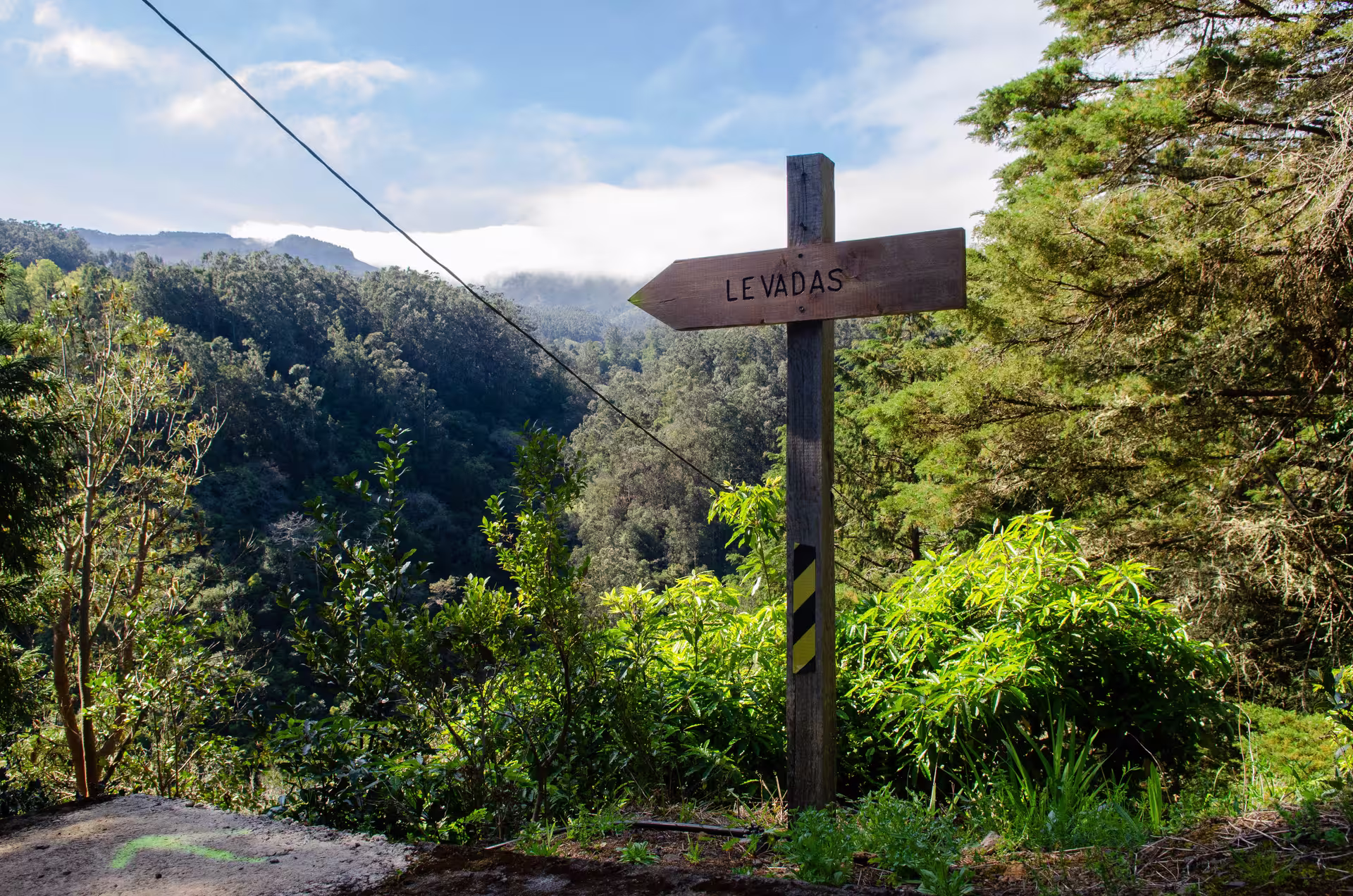Scenic view of Levada trail sign pointing towards verdant mountains on The Cardinal's Hike, ideal for adventure seekers.