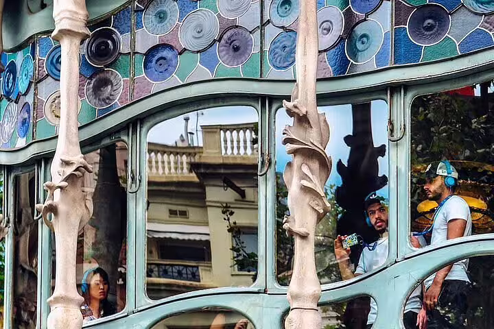 Tourists exploring Casa Batlló's intricate facade, featuring vibrant stained glass and Gaudí's organic architecture.