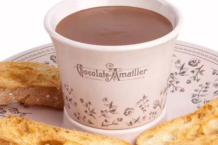 Cup of rich Amatller chocolate with crispy toast on a floral plate for the Casa Batlló & La Pedrera chocolate tour.