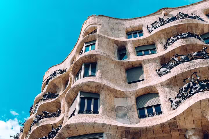 Stunning wavy stone facade of Casa Milà under a clear blue sky, highlighting Gaudí's architectural genius.