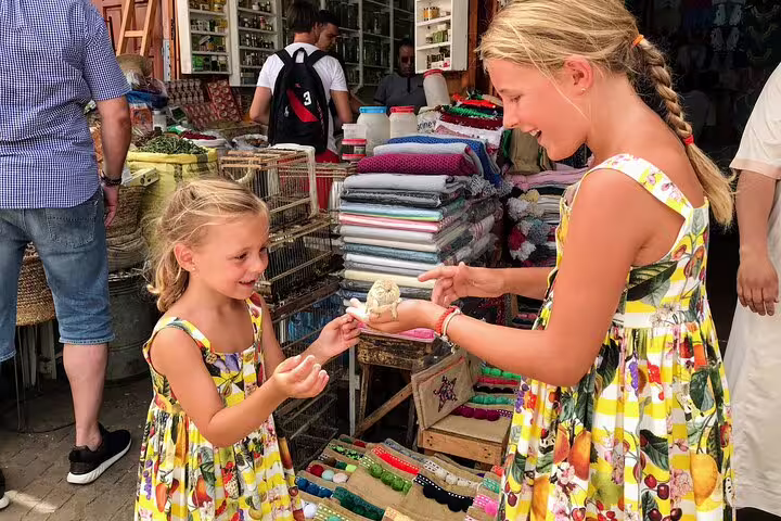 Girls browsing colorful stalls at Casablanca souk on a private day trip, shopping for local crafts and textiles