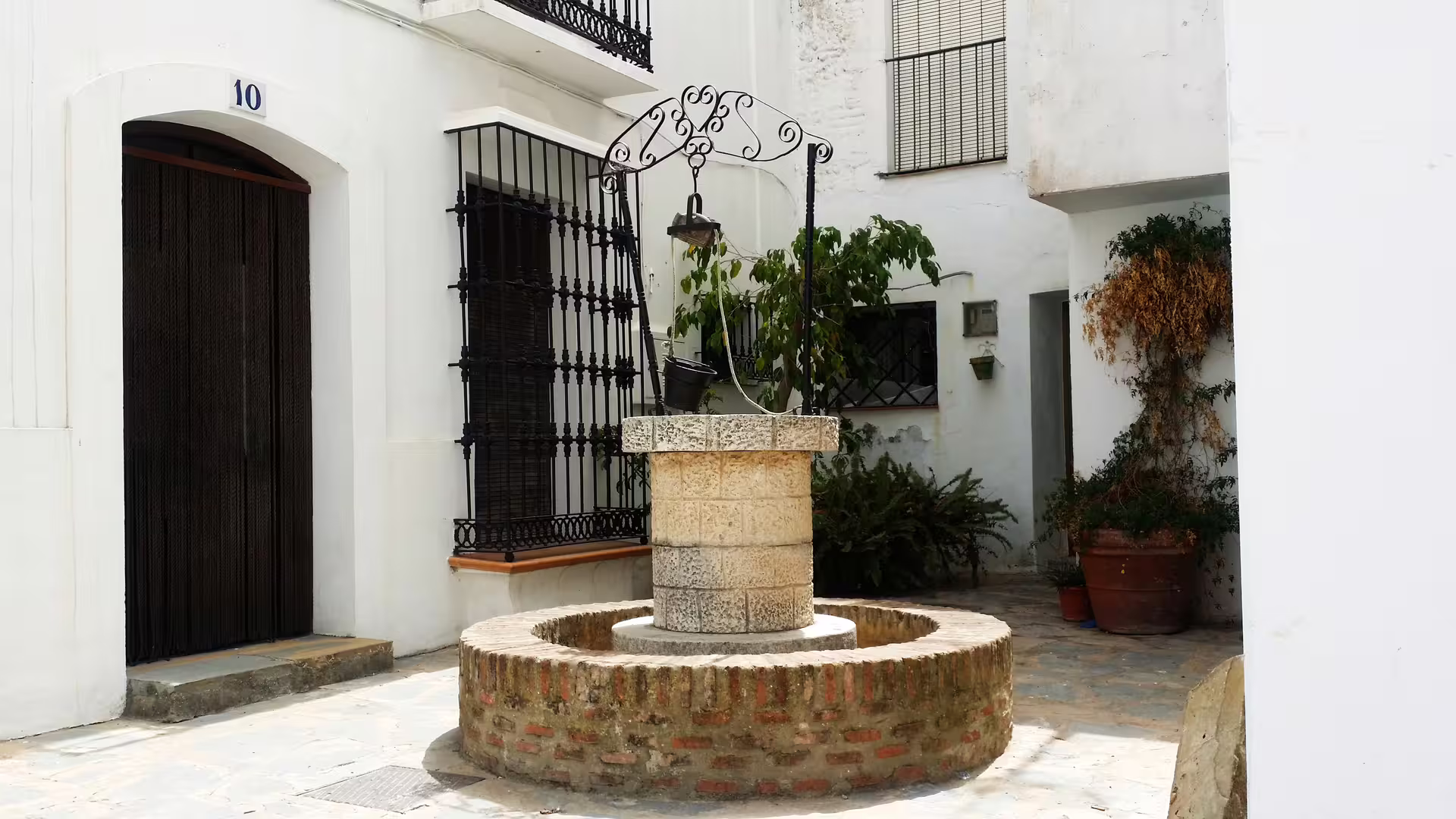 Traditional stone well in a whitewashed Casares courtyard on a private tour with hotel pick-up Costa del Sol