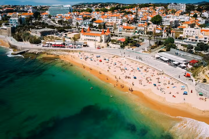 Aerial view of Cascais Beach with vibrant umbrellas and clear waters, showcasing an ideal Lisbon coastal getaway.