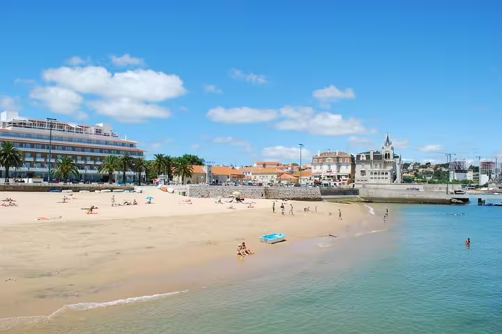 Scenic view of a sunny beach in Cascais, Portugal, showcasing the vibrant coastline included in a private Sintra and Cascais customizable day tour.