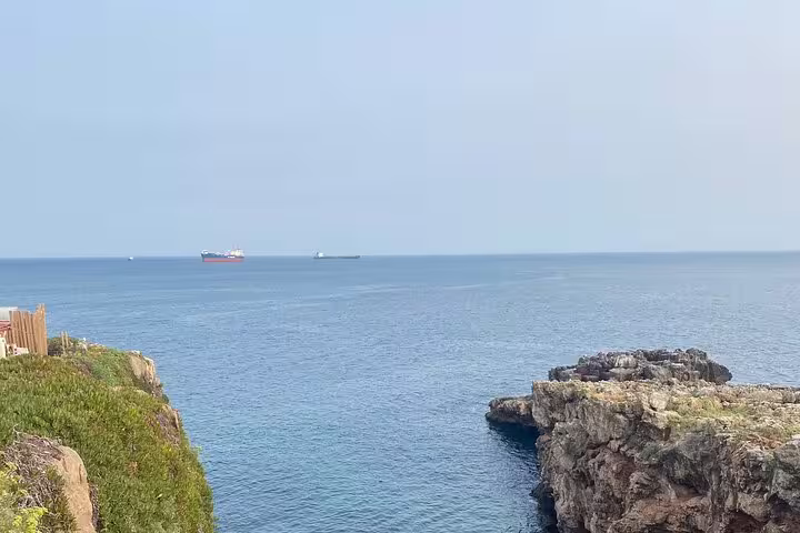 Calm ocean view with ships on the horizon and rugged cliffs in Cascais, showcasing Portugal's stunning coastal landscape.