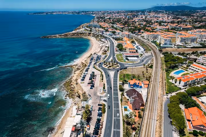 Aerial view of Cascais coastline showcasing scenic roads, beaches, and vibrant seaside atmosphere.