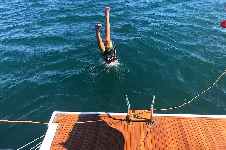 Guest diving into the Atlantic from a private sailboat in Cascais, swimming stop on a 2-hour cruise with drinks