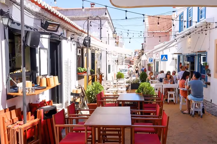 Quaint street in Cascais with charming outdoor cafes, perfect for relaxing on a small group tour to Sintra and beyond.