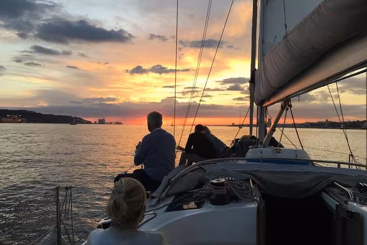 Guests relax on a private sailboat at sunset off Cascais, Portugal, on a 2-hour cruise with drinks