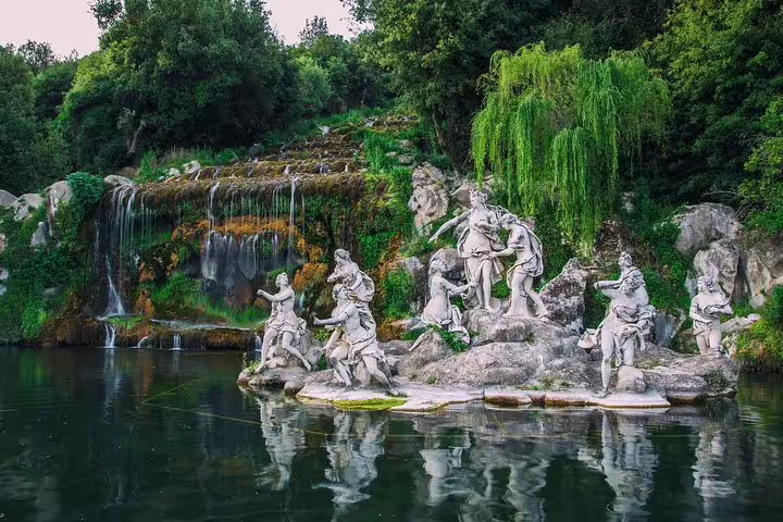Mythological statues and cascading waterfalls in the royal gardens of the Palace of Caserta on a small-group guided tour