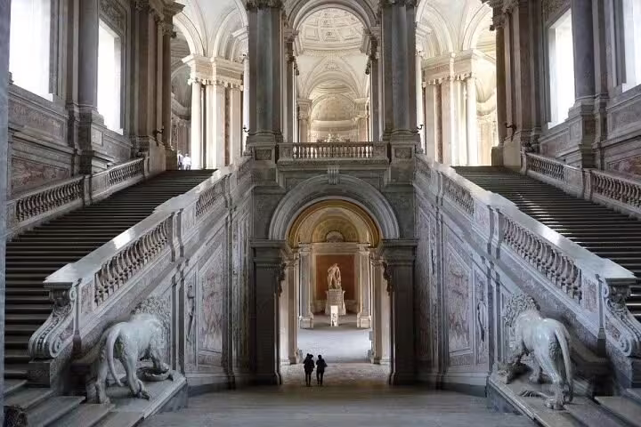 Grand marble staircase and baroque statues inside Caserta Royal Palace, Italy, visited on a guided private tour from Naples