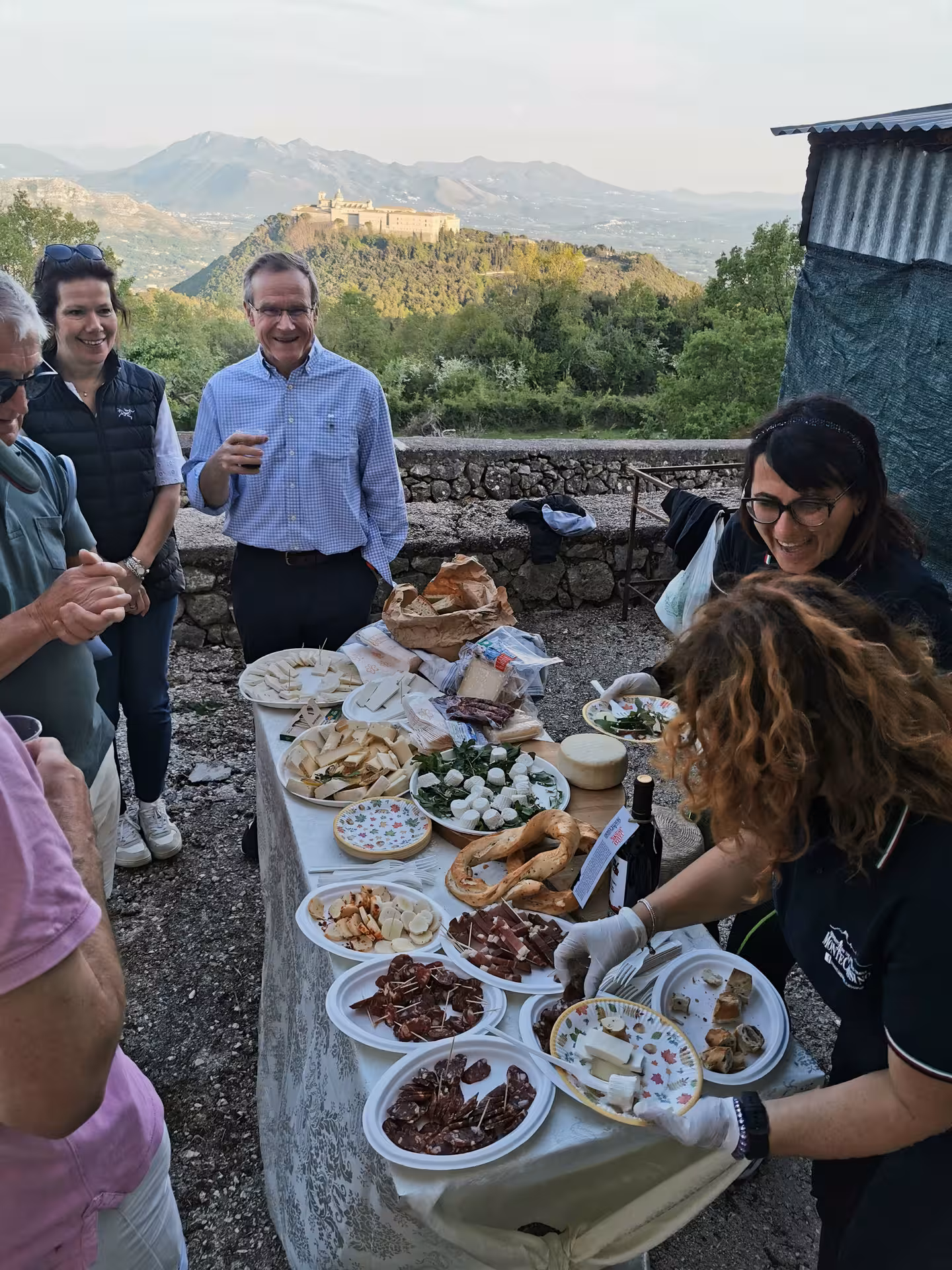 Tour group enjoying local delicacies with a scenic view of Cassino Abbey in the background.