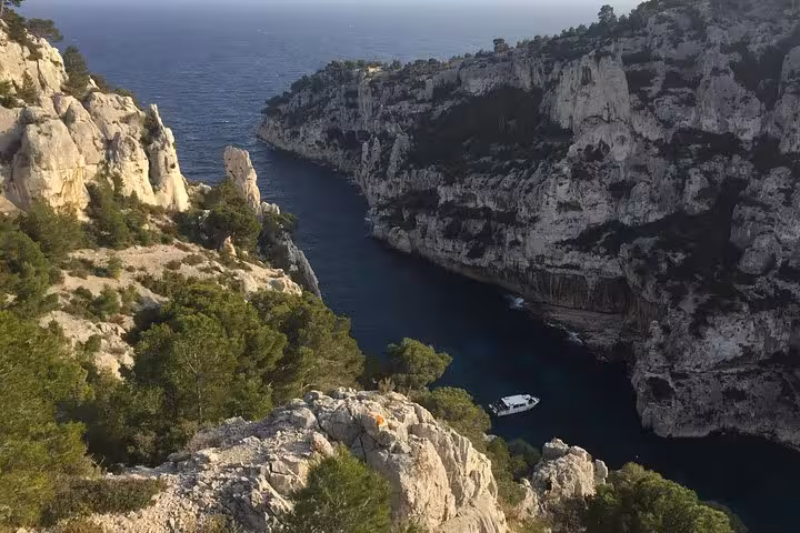 Scenic Calanques cliffs near Cassis with boat on turquoise inlet, Provence coast stop on wine tour