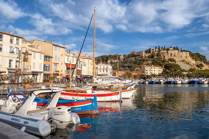 Picturesque Cassis harbor with vibrant boats and scenic cliffs, perfect for exploring on a wine tasting tour.