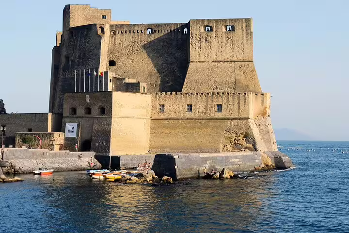 Historic Castel dell’Ovo fortress rising above the blue Gulf of Naples, seen from the water on a full-day catamaran tour