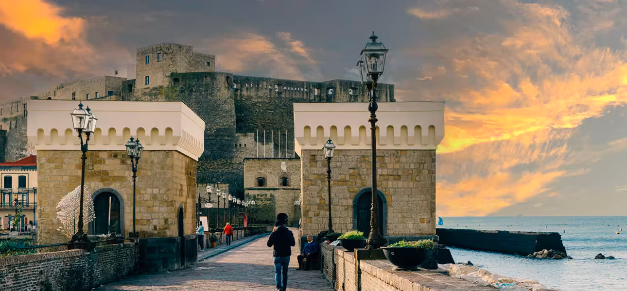 Scenic view of Castel dell'Ovo at sunrise on Naples Gulf tour, with vibrant skies and seaside charm.