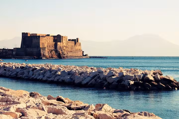 View of Castel dell'Ovo in Naples, Italy, surrounded by serene blue waters, perfect for a walking tour highlight.
