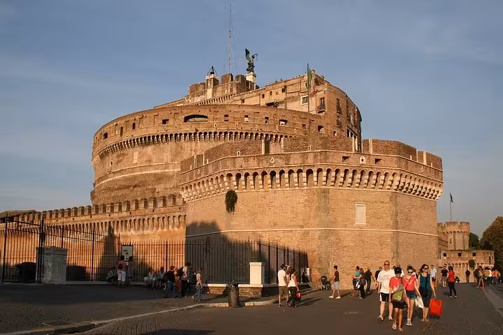 Tourists explore the historic Castel Sant'Angelo's exterior, admiring its ancient stonework and iconic structure in Rome.