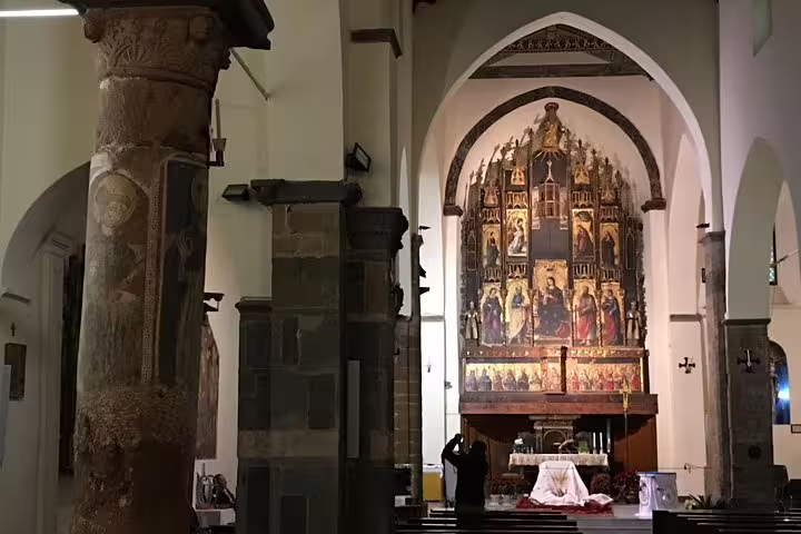 Interior of historic church in Castelbuono with ornate altarpiece, frescoed columns and visitor on a private tour from Palermo