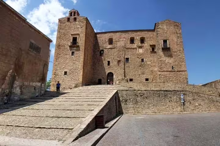 Historic Castelbuono fortress with stone ramp and medieval walls under blue sky, visited on private Monreale and Cefalù tour