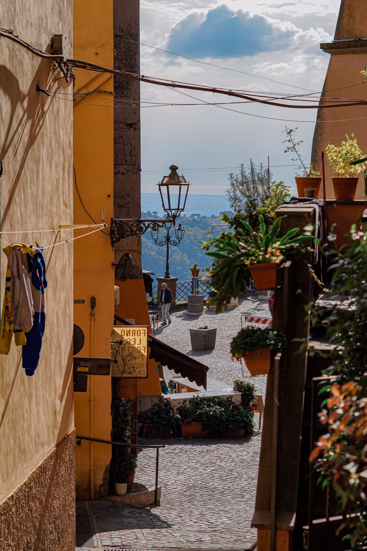 Charming narrow street in a historic town in Castelli Romani, with a view of the distant countryside and Lake Albano.