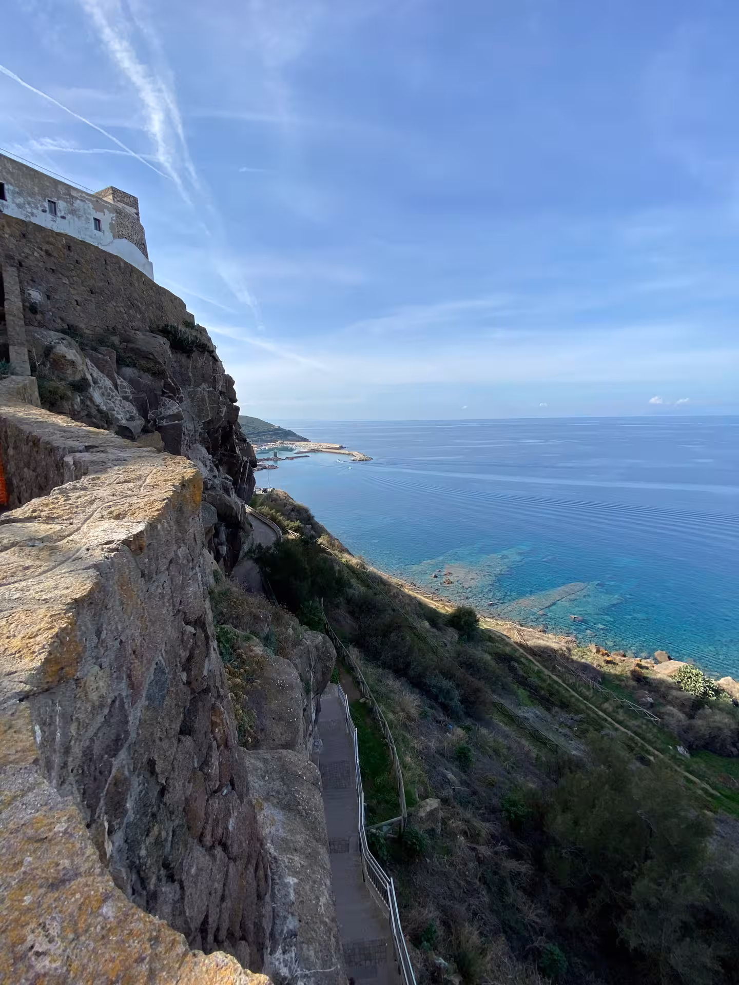 Scenic coastal view from Castelsardo's cliffs overlooking the Mediterranean Sea on a sunny day.