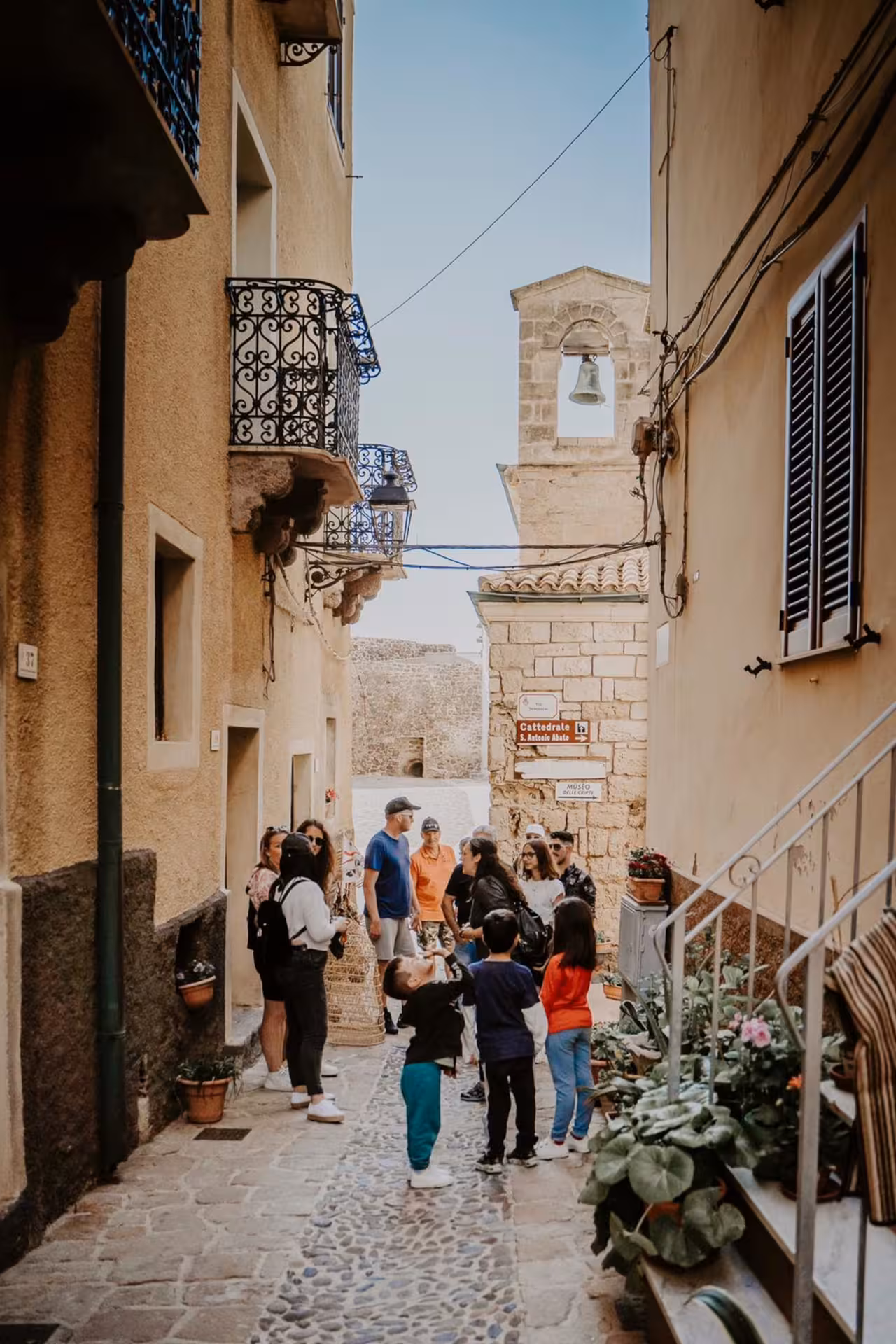 Tourists exploring a charming narrow street in Castelsardo near the Intreccio Museum.