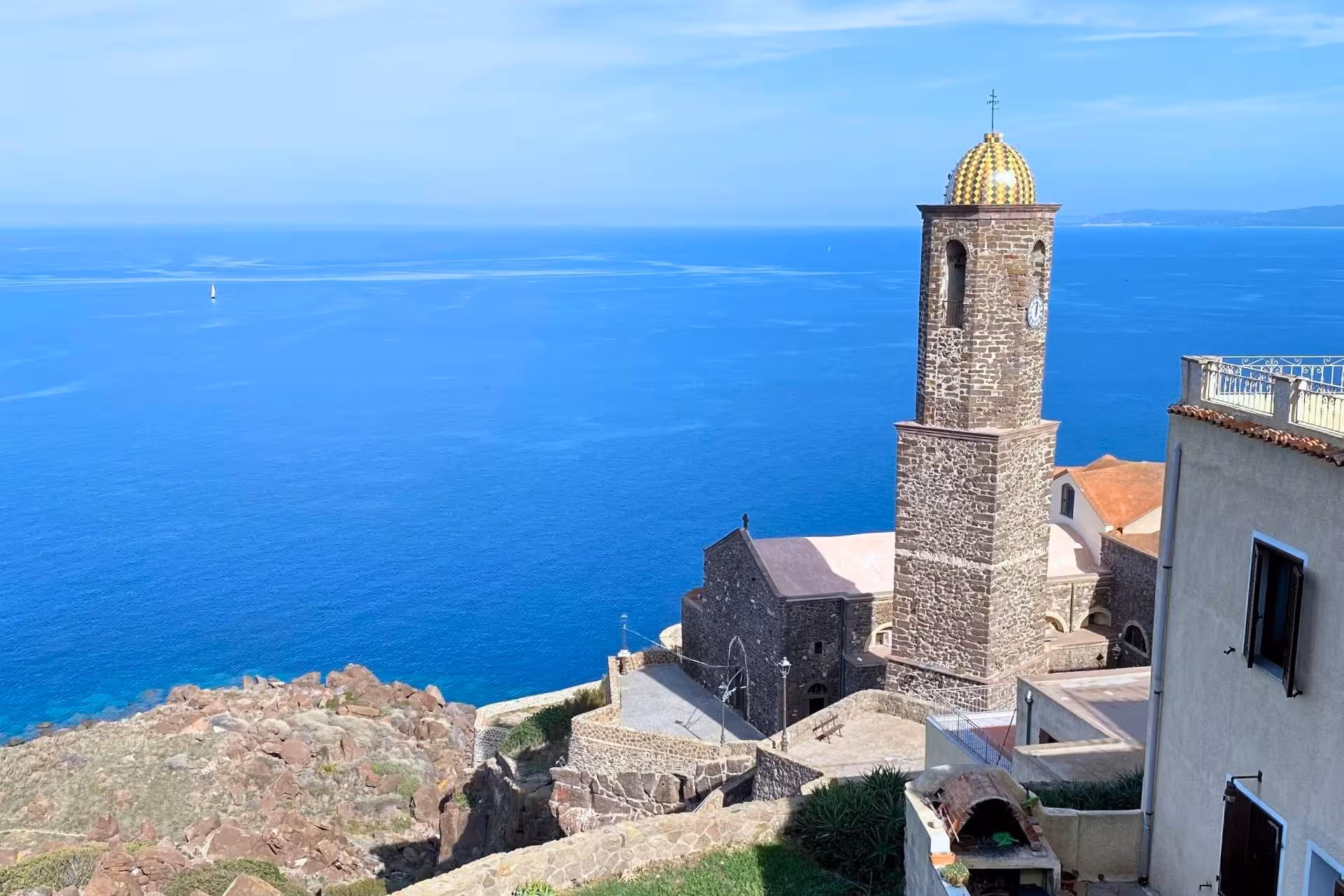 Scenic view of Castelsardo's church tower overlooking the vibrant blue sea, ideal for picturesque old town tours.