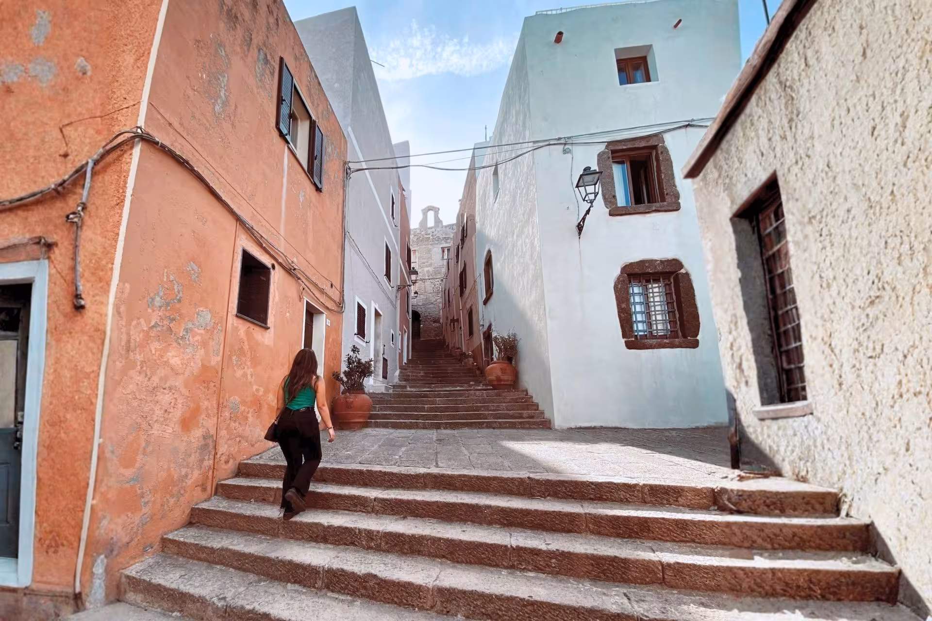 Tourist exploring charming narrow streets of Castelsardo old town, surrounded by colorful historic buildings.