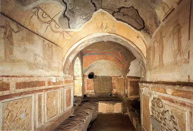 Frescoed early Christian burial chamber with arched ceiling and faded paintings in the Catacombs of Rome