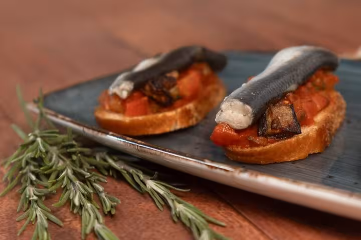 Enjoy traditional Catalan bruschetta topped with anchovies and tomatoes on the Gràcia Food Tour in Barcelona.