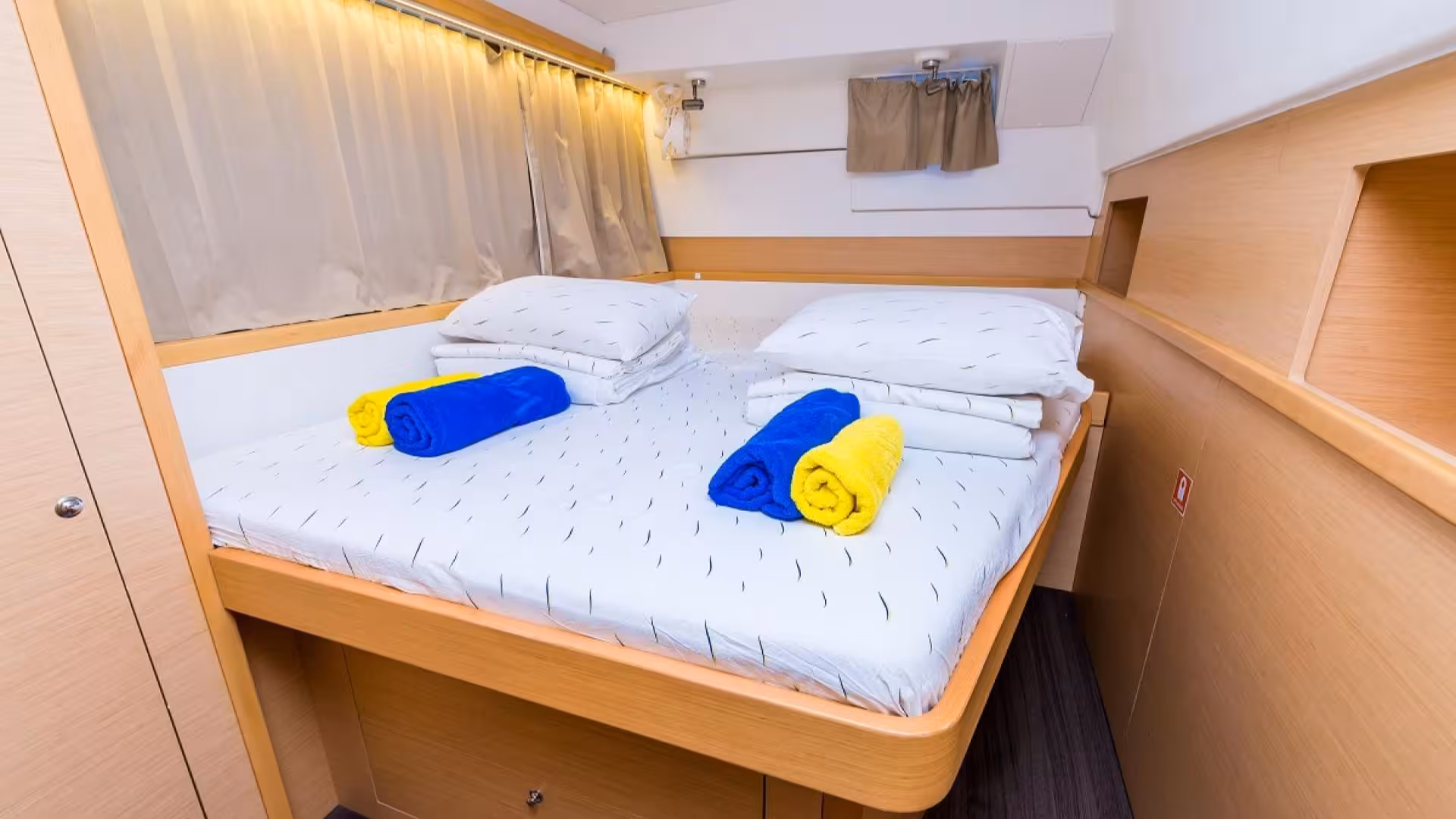 Comfortable catamaran bedroom with plush bedding, ready for a relaxing tour in the Tavolara Marine Protected Area.