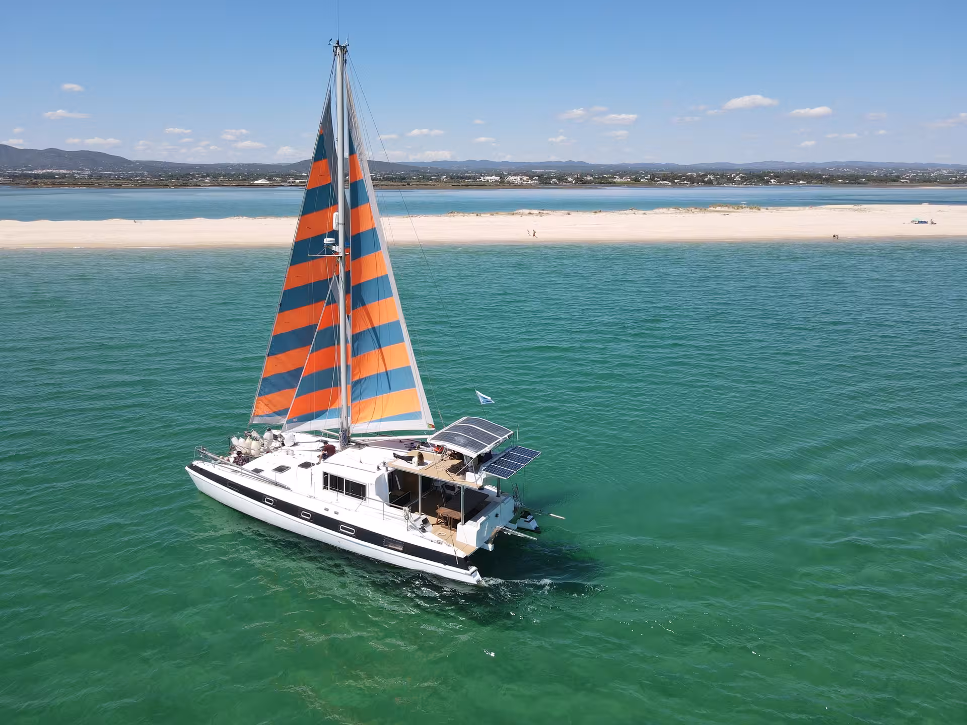 Aerial view of catamaran at Blue Lagoon sandbar on a full-day sailing trip, crystal water and Algarve coastline