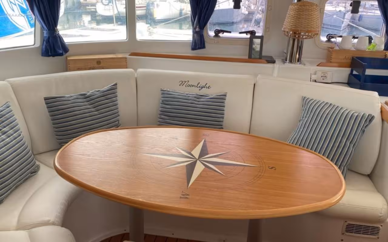 Cozy catamaran interior with elegant seating and a compass-themed table for La Maddalena Archipelago tour.