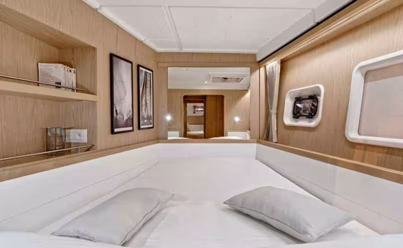Elegant bedroom on a catamaran featuring a comfortable bed, ambient lighting, and nautical-themed decor.