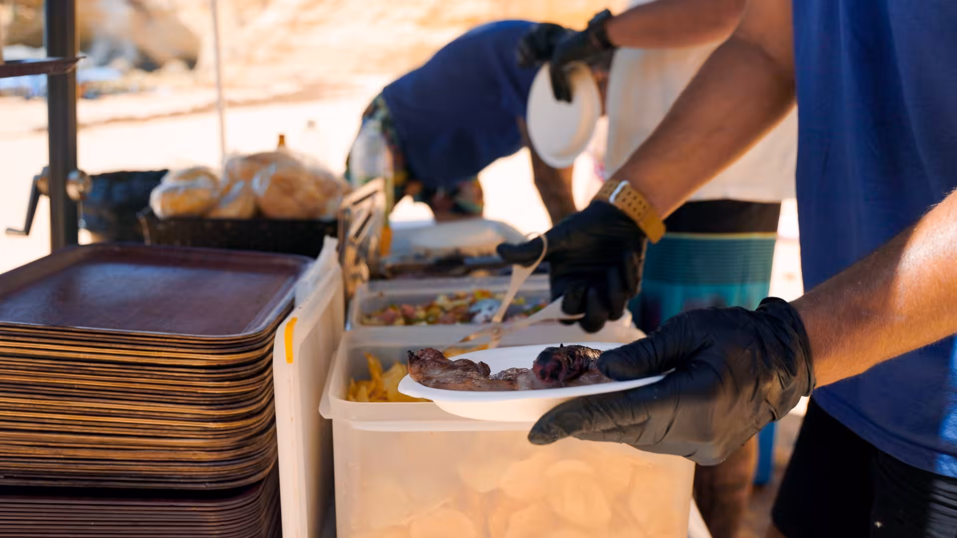 Guests serving delicious BBQ meats at the Catamaran MARA Beach BBQ Cruise buffet, highlighting a vibrant, beachside feast.