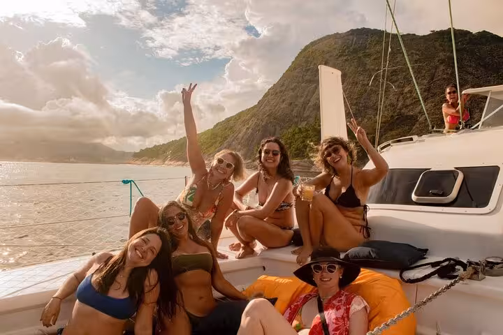 Friends relax on catamaran deck in Rio, enjoying open bar on a 3-hour private Velas do Rio sail