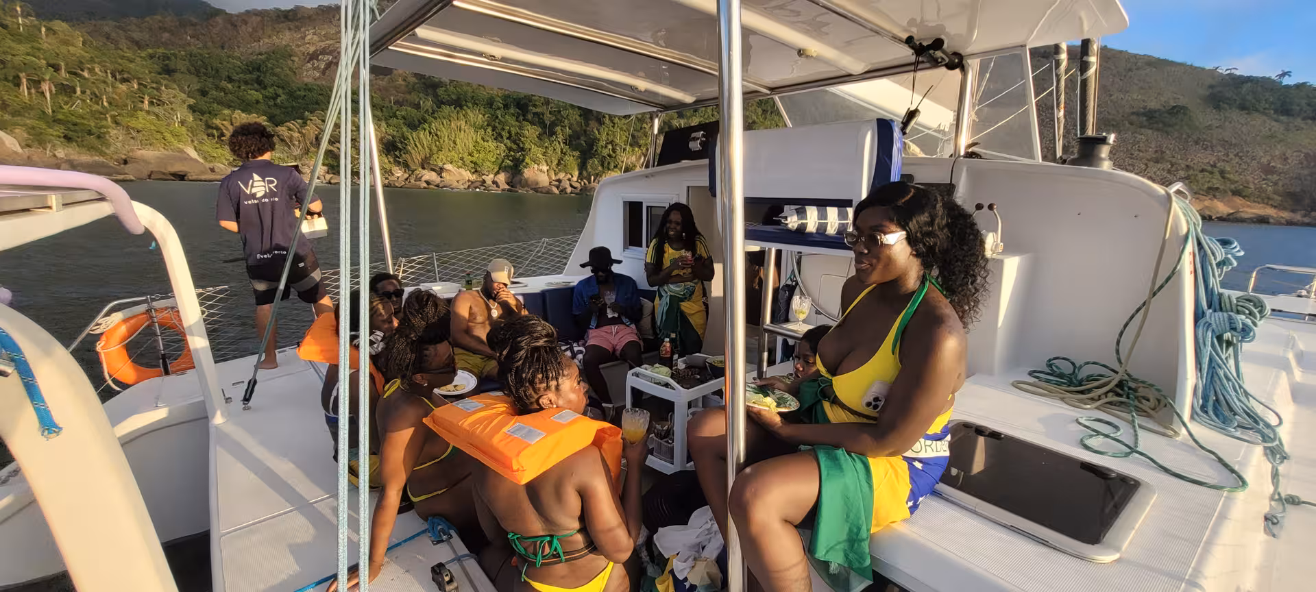 Guests relaxing onboard during Velas do Rio 3-hour shared catamaran sail, drinks and sunset vibes in Rio