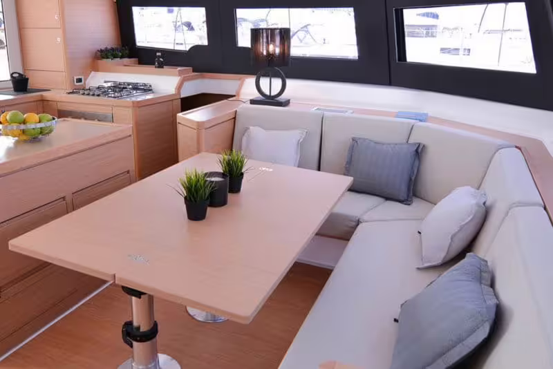 Stylish catamaran saloon with dining table, sofa seating and kitchenette, ideal for relaxing on a full-day Gulf of Naples tour