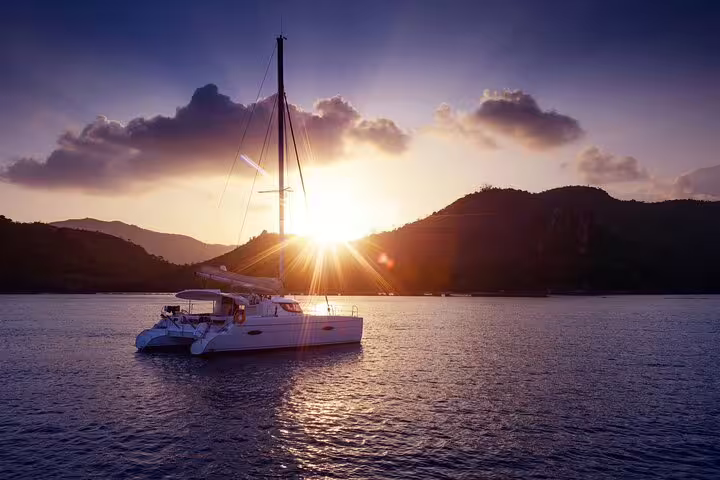 Catamaran sailing during a stunning sunset on a Formentera and Ibiza small group trip, highlighting serene coastal views.